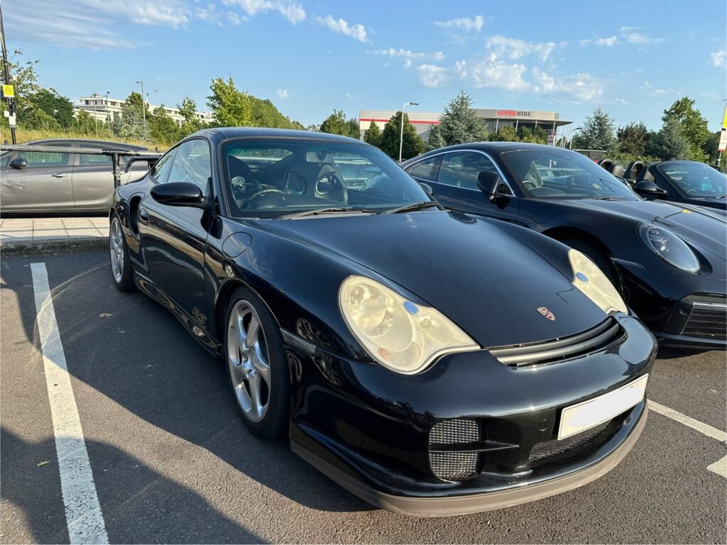 a black Porsche 996 Turbo parked in a parking lot